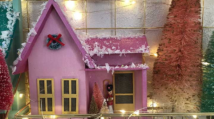 closeup of pink vintage wooden christmas village with bottle brush trees